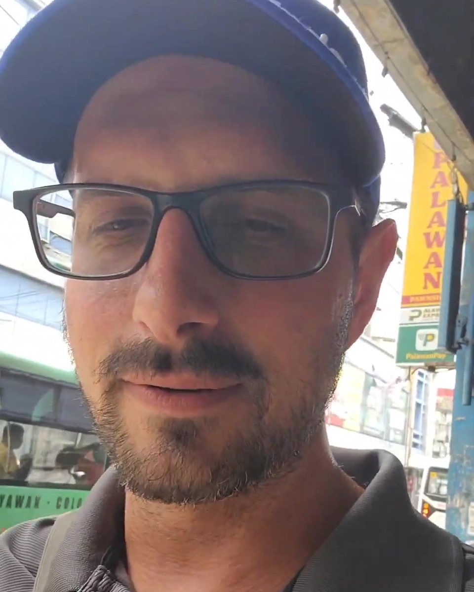 Todd Michael Gori in a blue cap, glasses and grey polo on a city street